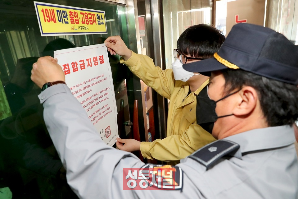 성동구 보건소 관계자와 경찰이 송정동 유흥업소에 집합금지 명령서를 붙이고 있는 모습